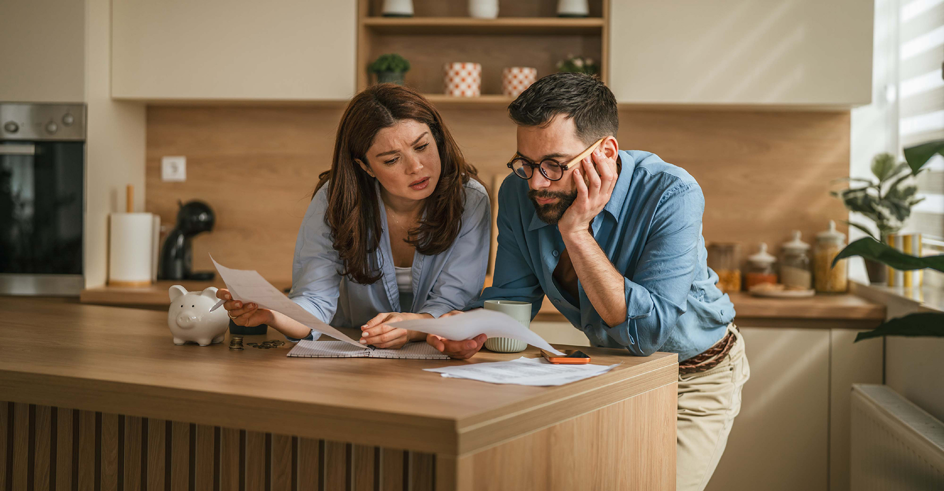 A couple is a the kitchen counter looking a documents and looking stressed.